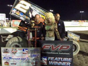 Danny Lasoski poses in Victory Lane with “Sandy is Dolly” and flagman Doug Clark Thursday at I-80 Speedway 